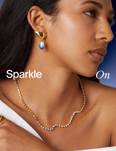 Model wearing gold earrings with a blue stone