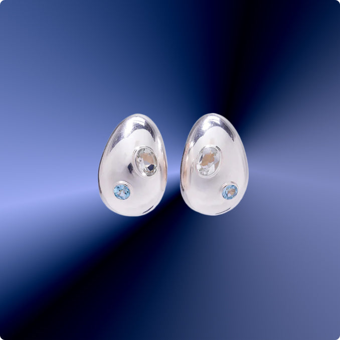 Silver earrings with blue and white diamonds on a blue gradient background